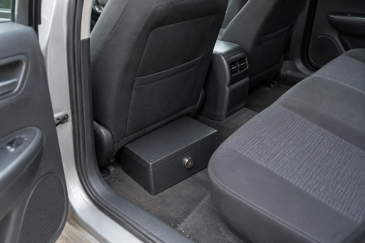 Closed steel lockbox on the floor of an empty parked car